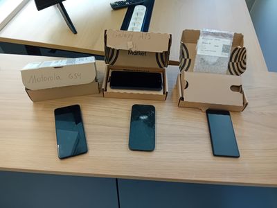 Plusieurs téléphones portables sont posés sur une table, recouverts de boîtes.