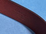 a close up of a brown leather belt on a blue surface