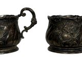 deux vases en argent posés l'un à côté de l'autre sur une surface blanche