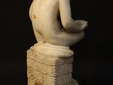 a statue of a boy sitting on top of a stone block