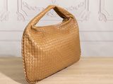 a brown woven bag sitting on top of a wooden table