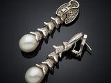 a pair of pearl and silver earrings on a black surface