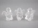 trois figurines blanches représentant des anges, posées sur une surface blanche