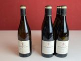 trois bouteilles de vin sont posées sur une table devant un mur rouge