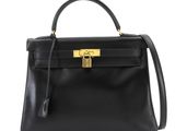 a black leather handbag with a gold lock on the handle