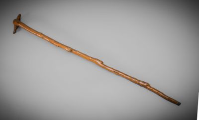 an old wooden walking stick with a wooden handle on a gray background