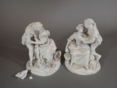 deux statues blanches représentant un homme et une femme assis sur un rocher