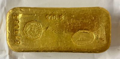 un lingot d'or est représenté sur une surface blanche