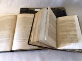 trois livres ouverts posés les uns sur les autres sur une table
