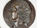 three bronze medallions of a man and a woman on a white surface