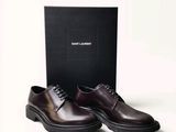 des chaussures en cuir marron pour homme devant une boîte noire sur fond blanc