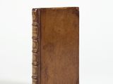un vieux livre à la couverture brune posé sur une surface blanche