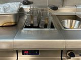une cuisine équipée d'un évier et d'une cuisinière sur laquelle sont posées de nombreuses casseroles et poêles