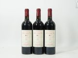 trois bouteilles de vin rouge sont alignées sur une surface blanche