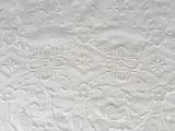 a close up of a white quilt with a pattern on it