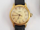 a gold wrist watch sitting next to a cup of coffee
