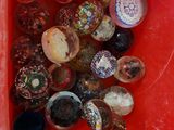 un récipient rouge rempli d'une multitude de perles de toutes sortes