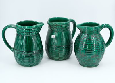 three green vases sitting next to each other on a white surface