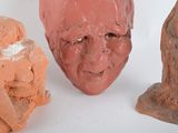 three clay sculptures of a man and a woman on a white surface