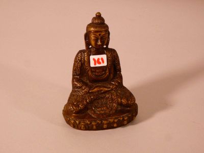 une petite statue représentant un Bouddha assis sur une surface blanche