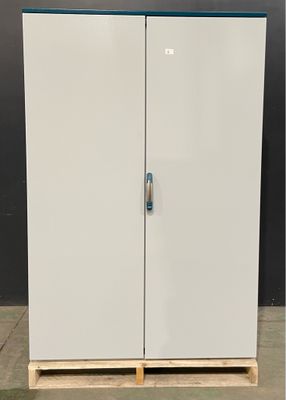 Deux armoires blanches munies de poignées bleues sont posées sur une palette devant un mur noir.