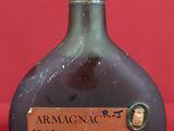 an old bottle of wine sitting on top of a red table
