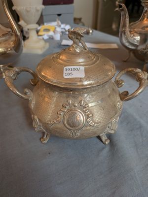 une théière en argent posée sur une table à côté d'autres théières en argent