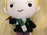a small stuffed doll of a boy with a green scarf