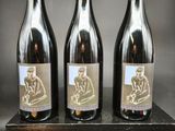 trois bouteilles de vin posées sur un bloc de bois