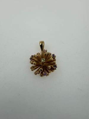 a gold pendant with a flower design on it