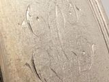 an old silver plate with writing on it sitting on top of a table