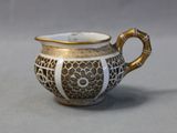 a white and gold tea pot with a gold handle