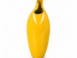 a yellow vase with a black top on a white background