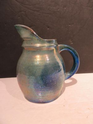 une carafe bleue et verte posée sur une table blanche