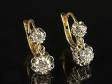 pair of diamond earrings on black surface with reflection