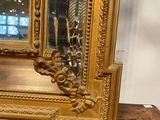 a gold frame with a mirror on top of a wooden table