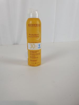 Le flacon de crème solaire est posé sur une surface blanche.