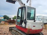 a red and white excavator that is sitting on the ground
