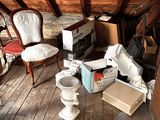 a room with a toilet, a chair, a box, and other items on the floor