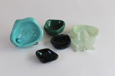 four pieces of green and black glass on a white surface