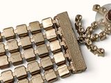 a gold bracelet with a chain and a glass bottle on it