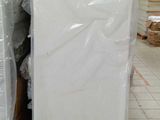 Des cartons contenant des matelas sont empilés les uns sur les autres dans un entrepôt