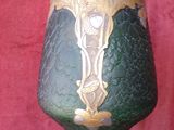 a green vase with a gold decoration on it