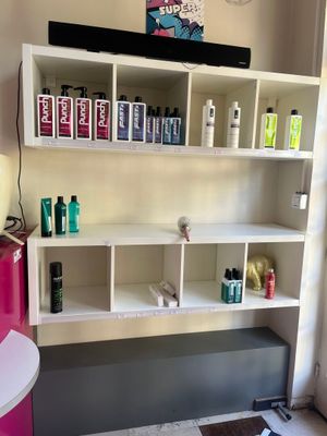 une pièce avec une étagère sur laquelle sont posés divers produits capillaires