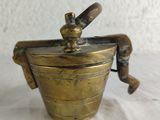 a small brass pot with a handle on a table