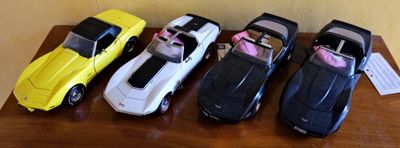 Plusieurs petites voitures sont alignées en rang sur une table.