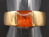 a close up of a gold ring with an orange stone in it