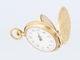 an antique gold pocket watch on a white background with a coin