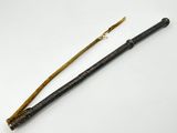 une vieille baguette magique avec un manche en bois posée sur une surface blanche