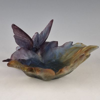 un bol en verre orné d'un oiseau, posé sur une surface blanche
